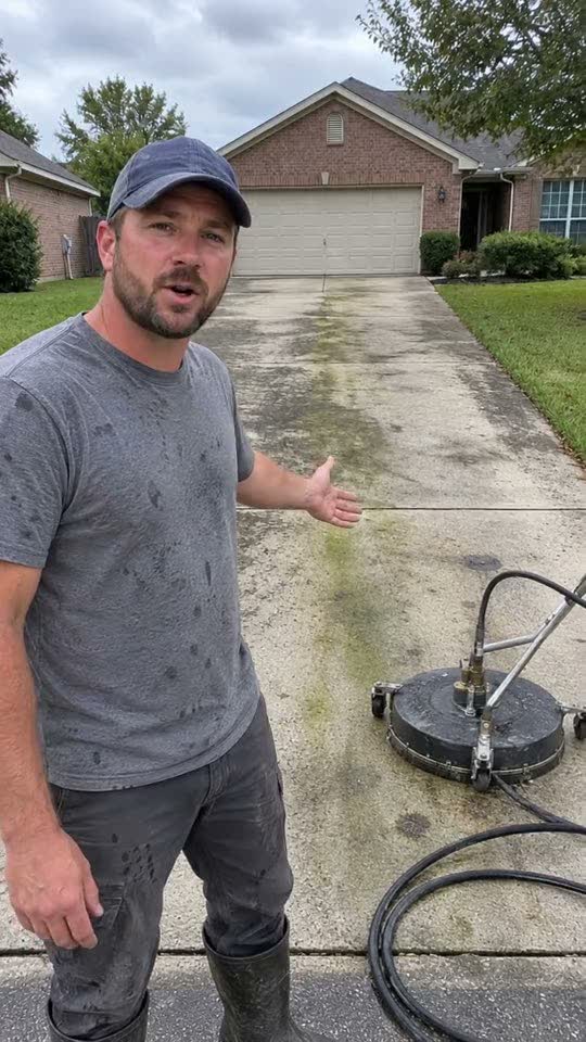 A pressure washer filming himself on a driveway
